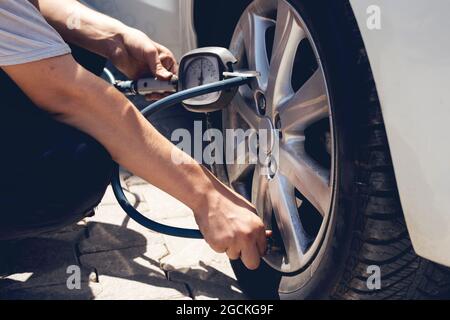 Nahaufnahme mechanisches Aufblasen des Reifens Hand hält den Druck des Manometers für die Überprüfung und das Einfüllen der Luft im Autoreifen. Fahrzeugkonzept. Stockfoto