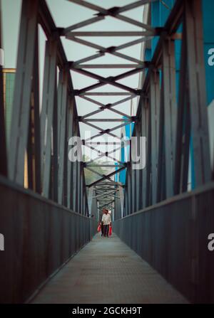 Männer gehen mit einer Tasche in der Hand durch eine Brücke zur Arbeit Stockfoto