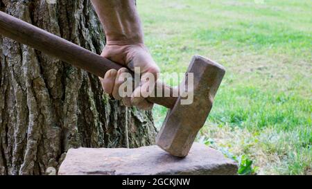 Eine Person, die einen Schlittenhammer verwendet, um einen Felsen aufzubrechen Stockfoto