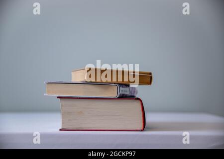 Auf dem Tisch stapelten sich drei Bücher, auf dem Hintergrund eine graue Wand Stockfoto