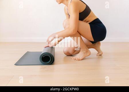 Seitenansicht der Ernte nicht erkennbar barfuß weibliche Rollmatte nach Yoga-Sitzung zu Hause Stockfoto