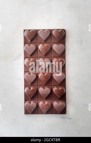 Draufsicht auf köstliche Schokoladen-Bonbons mit Nüssen in Herzform auf Marmortisch Hintergrund Stockfoto