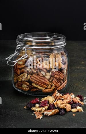 Glas mit Nüssen und getrockneten Früchten auf einem dunklen rustikalen Hintergrund Stockfoto