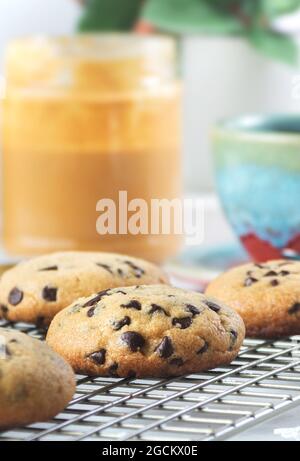Stillleben von frisch zubereiteten Schokoladenkeksen mit Erdnussbutter und Streuseln neben einem Kaffee Stockfoto