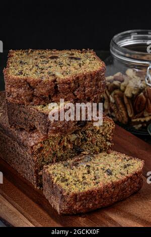 Karottenkuchen in Stücke geschnitten, auf einem Holz neben einem Glas voller Walnüsse gestapelt Stockfoto