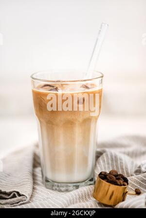 Gekühlter Latte-Kaffeedrink in einem hohen Glas mit Glasstroh Stockfoto