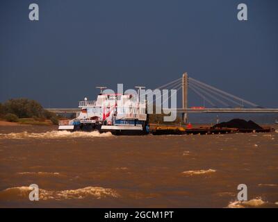 Großes Handelsschiff mit Fracht, das unter einer Brücke auf dem Rhein in Deutschland passiert Stockfoto