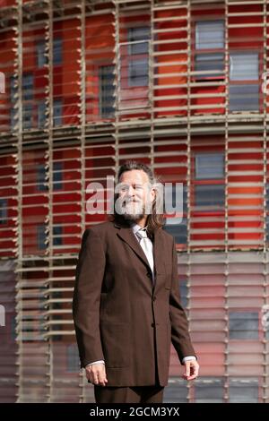 Positiver bärtiger Mann mittleren Alters in Business-Style-Outfit, der pensiver gegen das Stadtgebäude schaut Stockfoto