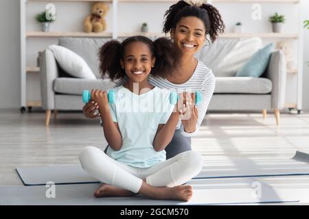 Positive afroamerikanische Mutter und Tochter mit Langhanteln Stockfoto