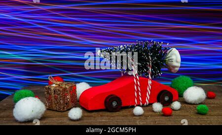 Weihnachtsdekoration mit kleinem roten Auto und bunten Lichtern dahinter Stockfoto