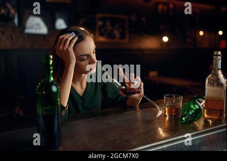 Unglückliche Frau trinkt Alkohol an der Theke in der Bar Stockfoto