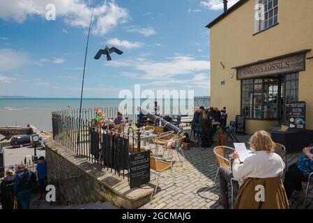 Dorset Coast, Blick auf Menschen entspannen auf einer Café-Terrasse mit Blick auf die Küste in Lyme Regis, Dorset, England, Großbritannien Stockfoto