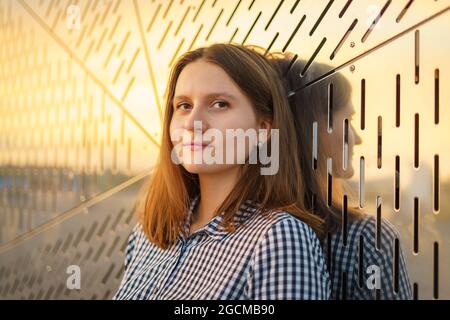 Junge Blondine, die die Kamera anschaut und lächelt. Reflexion des Sonnenlichts vom Sonnenuntergang Stockfoto