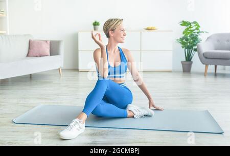 Die Dame praktiziert Yoga und sitzt in der Ardha Matiendrasana-Pose Stockfoto