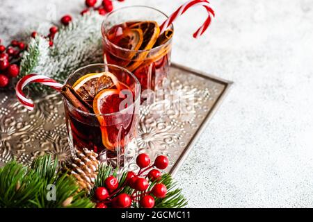 Zwei Gläser Glühwein mit Gewürzen und Weihnachtsschmuck auf einem Metalltablett Stockfoto