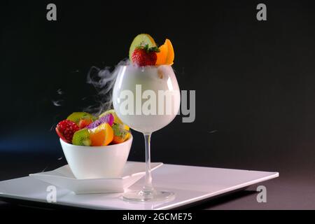 Obstsalat mit eisweißer Rauchmilchcreme in einem schönen Weinglas Stockfoto