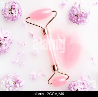 Roller Gesichtsmassager und Flieder in Milch . Gesichtspflege. Hautpflege. Kosmetologie. Massage. Fliederbuchse. Speicherplatz kopieren Stockfoto