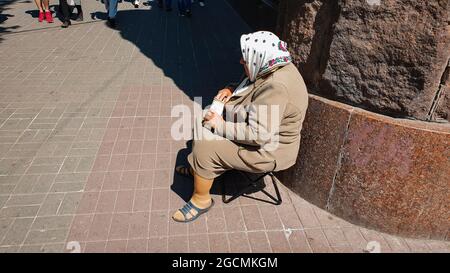 Kiew, Ukraine-1. Mai 2018: Ältere traurige Frau bettelt Geld, während sie auf einem Stuhl in der Kreschatik-Straße in Kiew, Ukraine, sitzt. Stockfoto