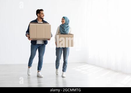 Lächelndes muslimisches Paar zieht in eine neue Wohnung, Foto in voller Länge Stockfoto