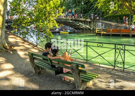 Zwei Liebende vor der Brücke der Liebenden in Annecy beobachten an einem Sommertag die vorbeiziehenden Touristen. Annecy, Département Savoie, Frankreich Stockfoto