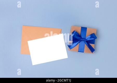 Umschlag, leeres Papierkartenmockup und Geschenkkarton auf blauem Hintergrund. Geschenk und Brief für Vatertag. Stockfoto
