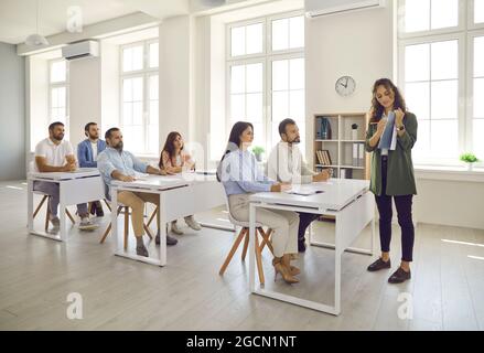 Erfahrene Geschäftscoach-Frau erklärt erwachsenen Studenten die Strategie eines Marketing-Seminars. Stockfoto
