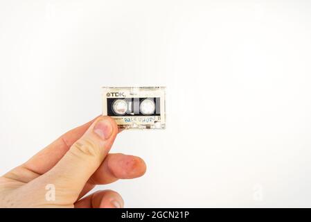 MAILAND, ITALIEN - 15. Jul 2021: Eine Hand, die ein altes Audio-Mikrokassettenband hält, das auf weißem Hintergrund isoliert ist Stockfoto