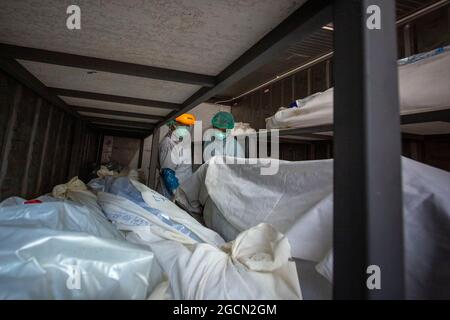 Khlong Luang, Pathum Thani, Thailand. August 2021. Das Personal der Leichenhalle lädt die Leichen der Abteilung für Gerichtswissenschaft des Universitätskrankenhauses Rangsit der Thammasart University in einen umgebauten Schiffscontainer, der auf Covid-19-Tests wartet. (Bild: © Adryel Talamantes/ZUMA Press Wire) Stockfoto