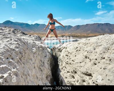 L Los Escullos Strand im Naturpark Cabo de Gata, Nijar.Frau mit Bikini in den Steinen zu Fuß Stockfoto