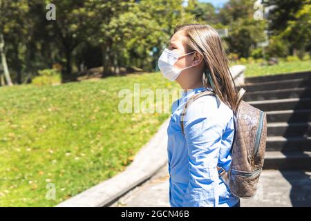 Portrait von blonde Mädchen mit Maske und Rucksack im Freien. Zurück zur Schule Stockfoto