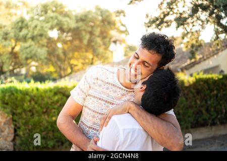 Ein Junge küsst seinen Freund. Ein homosexuelles Paar genießt ihre Liebe. Ein lächelnder junger Mann, der einen Kuss von seinem Liebhaber mit Naturhintergrund bekommt. Glücklich Stockfoto
