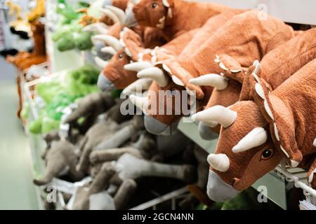 Nahaufnahme von Spielzeug-Dinosauriern in den Regalen. Verschwommenes weiches Spielzeug auf dem Hintergrund. Spielwarenladen. Stockfoto