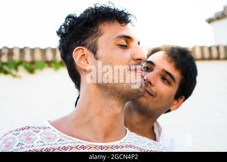 Ein junges schwules Paar in der Liebe. Zwei junge schwule Jungs im Sommer im Freien. Stolzes Paar brauner kaukasischer Jungen mit Sonnenuntergang im Hintergrund. Glückliches Paar Stockfoto