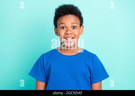 Foto von funky Brunet kleinen Jungen tragen blaues T-Shirt isoliert auf blauem Hintergrund Farbe Stockfoto