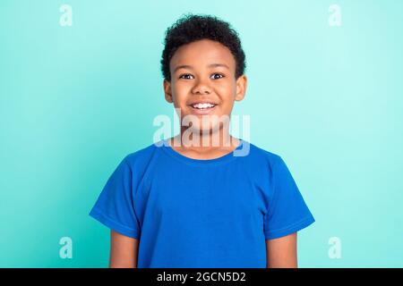 Foto von kühlen Brunet kleinen Jungen tragen blaues T-Shirt isoliert auf blauem Hintergrund Farbe Stockfoto