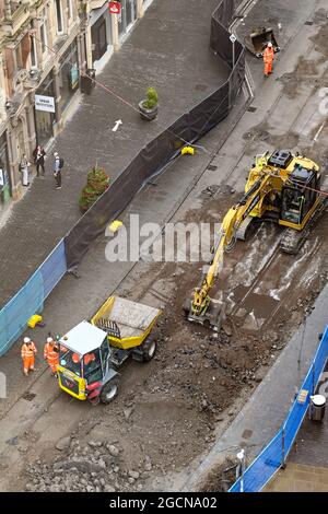 Birmingham, England - August 2021: Luftaufnahme eines mechanischen Baggers, der die Straßen- und Straßenbahnschienen in einer der Straßen im Stadtzentrum aufgräbt. Stockfoto