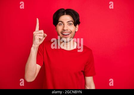 Foto von smart kreativen Kerl Aufstieg Finger haben große Idee aufgeregt Gesicht tragen rote T-Shirt isoliert roten Hintergrund Stockfoto