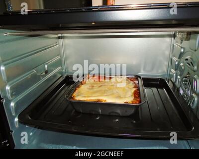 Hausgemachte Lasagne wird in einem heißen Ofen gebacken Stockfoto