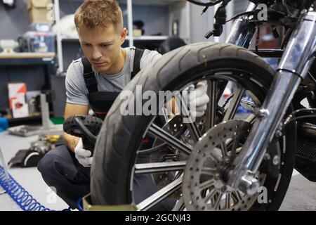 Der Mann überprüft den Reifendruck auf dem Motorrad in der Werkstatt Stockfoto