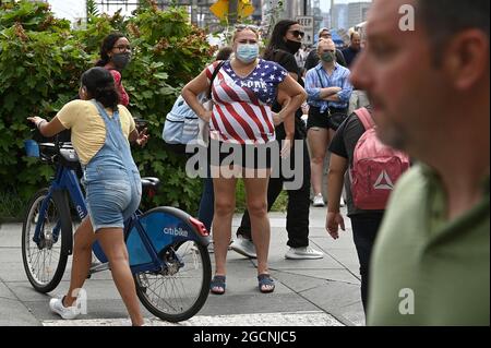 New York City, USA. August 2021. Eine Frau sieht zu, wie Demonstranten vor dem Rathaus eine Kundgebung gegen COVID-19-Impfungen und Impfmandate abhalten, New York, NY, 9. August 2021. New York wird die erste Stadt sein, die ab dem 16. August nicht geimpfte Menschen aus Innenrestaurants, Fitnessstudios und Unterhaltungseinrichtungen verbannt, deren Durchsetzung am 13. September beginnt; die Delta-Variante des Coronavirus hat in den Vereinigten Staaten einen Anstieg der COVID-19-Infektionen verursacht, vor allem unter den nicht geimpften. (Anthony Behar/Sipa USA) Quelle: SIPA USA/Alamy Live News Stockfoto