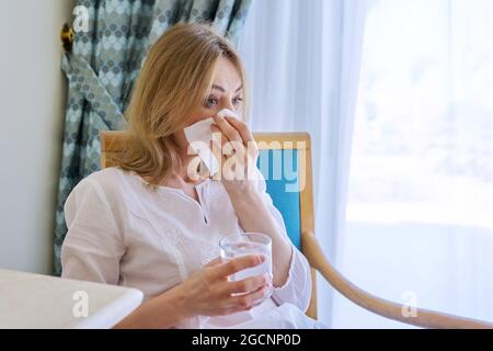 Aufgeregt weinende reife Frau mit Taschentuch zu Hause sitzen Stockfoto