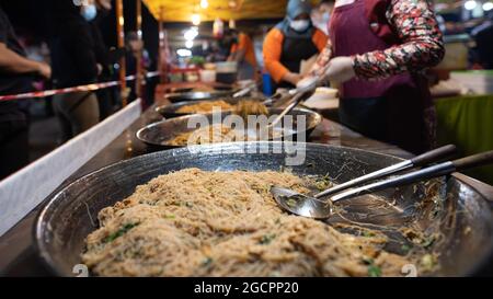 Street Food Nachtmarkt in Putrajaya, in der Nähe von Kuala Lumpur. Ein gebratener Nudelladen auf dem frischen Markt Putrajaya. Das Band neben dem IT-Bereich sorgt für soziale Netzwerke Stockfoto