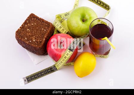 Roggenbrot mit grünen und roten Äpfeln und Saft in einem Glas auf einem weißen Teller mit gelbem Maßband. Diät und gesunde Ernährung Konzept Stockfoto