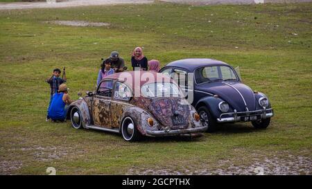 Putrajaya, Malaysia - 11. Oktober 2020: Zwei malaiische Familien treffen sich mit ihrem alten Volkswagen Käfer in einem Park in Putrajaya. Zwei gut restaurierte VW Käfer Stockfoto