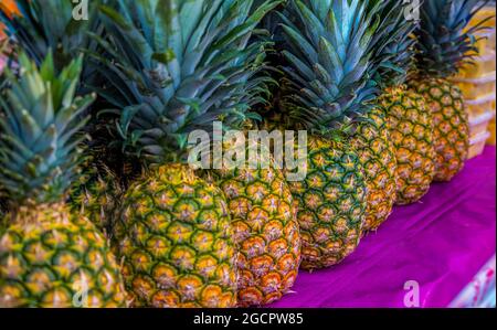 Nahaufnahme einiger Ananas auf einem frischen Markt in Kuala Lumpur, Malaysia. Frische Ananas liegen auf einem Verkaufsstand auf einem sogenannten Nassmarkt auf einer Theke. Stockfoto