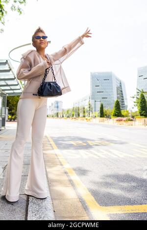 Kuala Lumpur, Malaysia - 10. Dezember 2020: Junge Asiatin mit schwarzer Handtasche an einer Bushaltestelle auf einer Straße in Kuala Lumpur, Malaysia. Jung und trendig Stockfoto