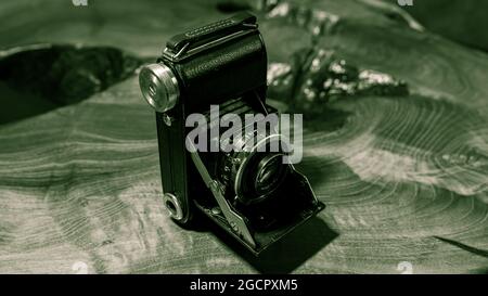 Leipzig, Sachsen, Deutschland - 1. Oktober 2020: Alte zerkratzte und staubige Fotokamera, mit klappbarem original Carl Zeiss Objektiv, stehend auf einem antikem Holz Stockfoto