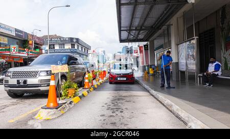 Taxistand in Kuala Lumpur. Taxifahrer wartet auf Kunden. Die traditionellen Taxis werden immer mehr durch Grab-Fahrer ersetzt. Ein Rot und Weiß Stockfoto