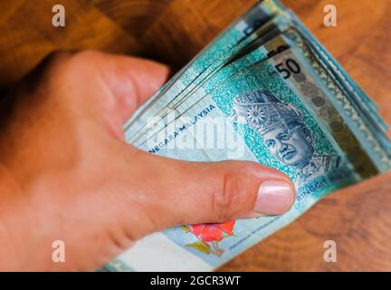 Eine Sammlung von fünfzig malaysischen Ringgit-Banknoten in einer männlichen Hand. Man Hand zeigen Malaysia Ringgit Banknoten. Jungen Hände halten Geld von Malaysia. Asien Stockfoto