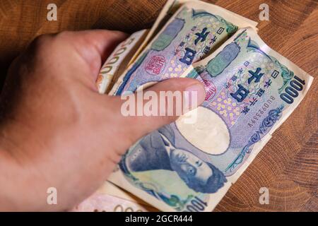 Männliche Hände zeigen japanischen Yen. Yen ist die Währung Japans. Auf der Vorderseite der Banknoten Hideyo Noguchi, Bakteriologe aus dem 20. Jahrhundert Stockfoto